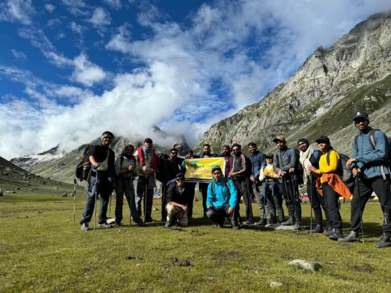 Trekkers at scenic campsite surrounded by mountains on Hampta Pass trek